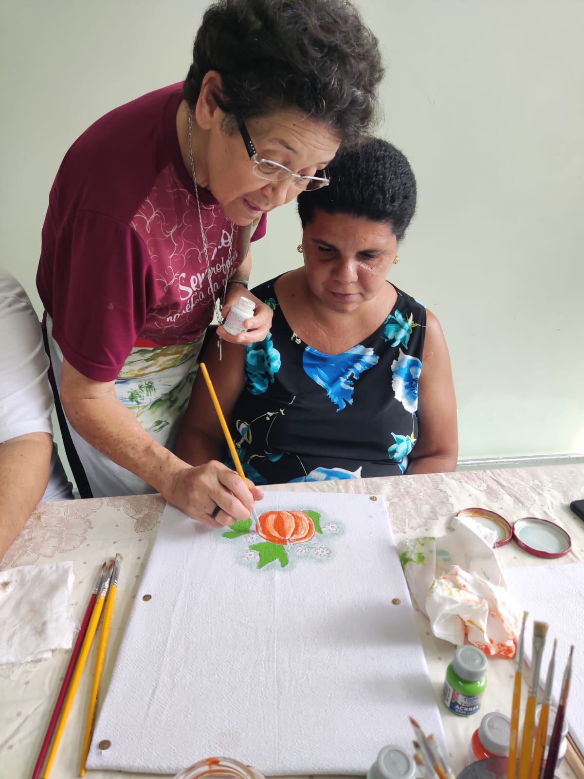 Missionária acompanhando com carinho uma mulher em atividade de pintura